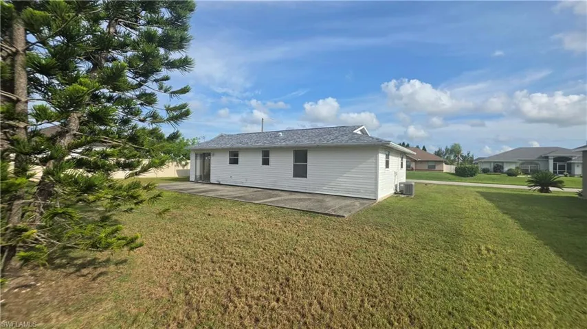 Rear exterior featuring white horizontal siding, a gray shingle roof, and a concrete patio