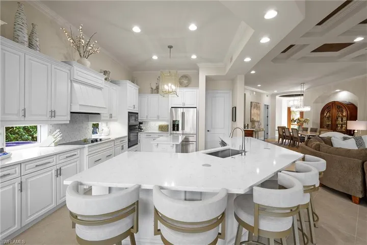 Kitchen with a large island, sink, crown molding, decorative light fixtures, and black appliances