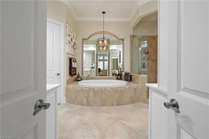 Bathroom featuring tile patterned flooring, ornamental molding, an inviting chandelier, soaking tub  and independent shower