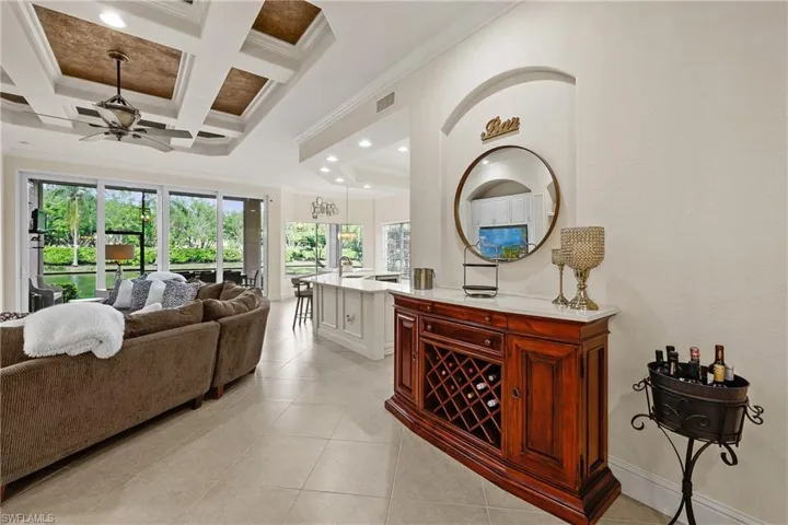 Bar with beam ceiling, ceiling fan, crown molding, and coffered ceiling