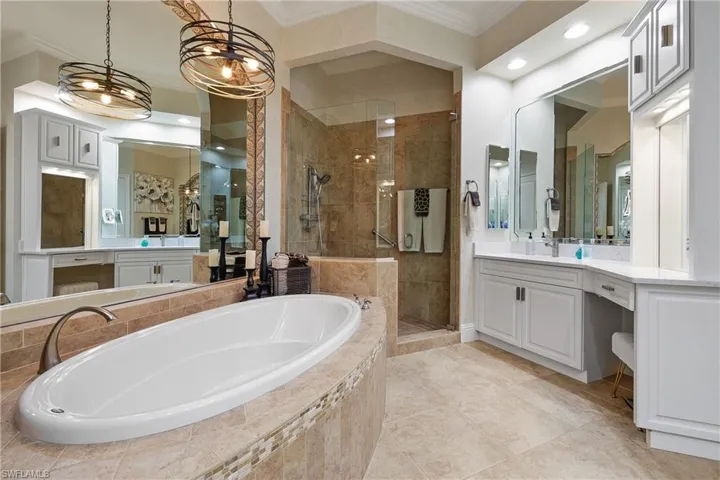 Bathroom featuring tile patterned flooring, a notable chandelier, separate shower and tub, her vanity with makeup, and ornamental molding