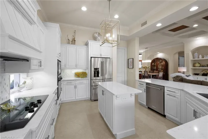 Kitchen featuring a center island, black appliances, white cabinets, crown molding, and a chandelier