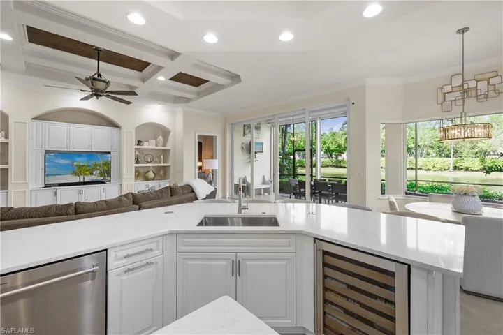 Kitchen with white cabinetry, sink, beverage cooler, coffered ceiling, and ornamental molding