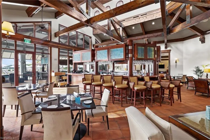 Dining space featuring beam ceiling, tile patterned flooring, high vaulted ceiling, and indoor bar
