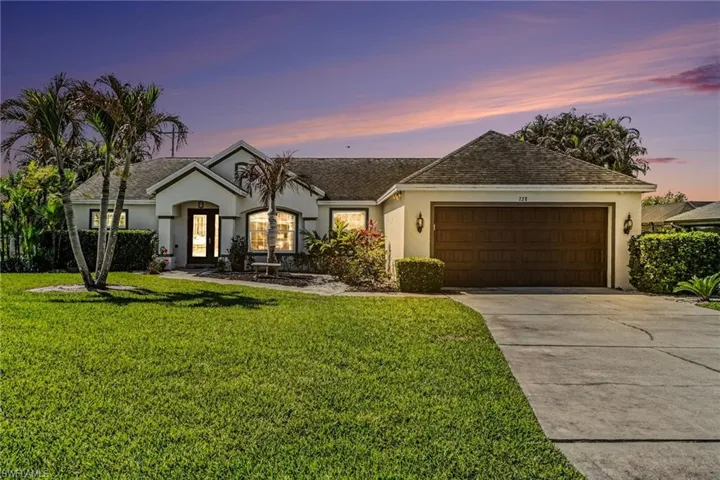 View of front of property featuring stucco siding, a garage, driveway, a front yard, and roof with shingles