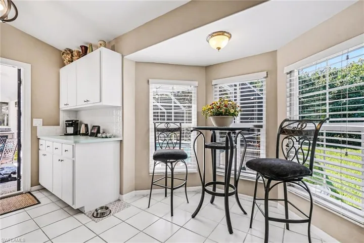 Kitchen with light countertops, tasteful backsplash, white cabinetry, and light tile patterned floors