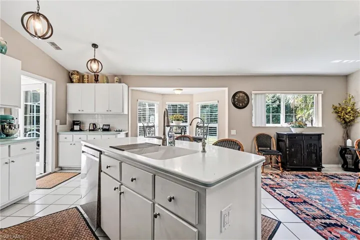 Kitchen with a center island, light countertops, white cabinetry, light tile patterned floors, and decorative backsplash