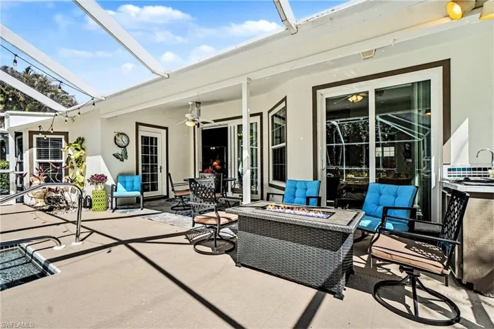 View of patio / terrace with a fire pit, ceiling fan, a sunroom, outdoor dining space, and a lanai