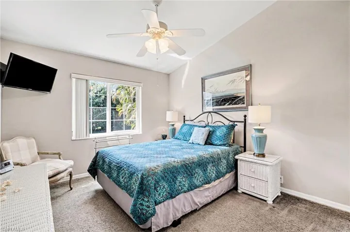 Carpeted bedroom featuring lofted ceiling and ceiling fan