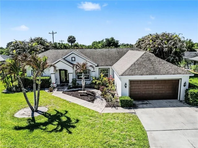 Ranch-style house with a garage, driveway, a front yard, and a shingled roof