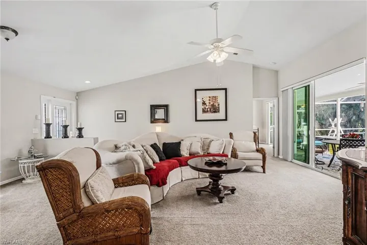 Carpeted living area with ceiling fan and vaulted ceiling