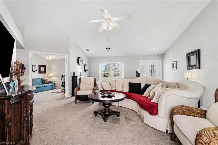Carpeted living area featuring ceiling fan and vaulted ceiling