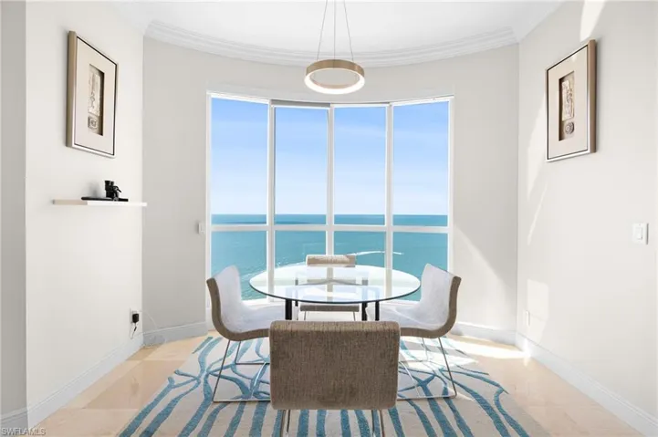 Tiled dining room featuring a water view, a healthy amount of sunlight, and ornamental molding