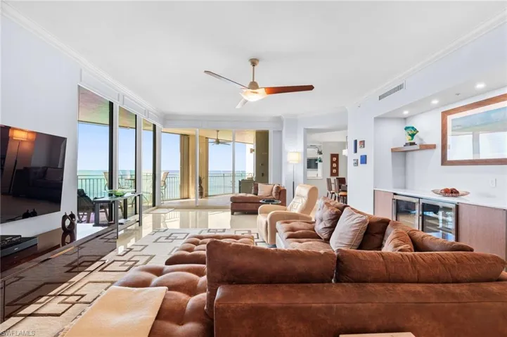 Living room with ornamental molding, a water view, and ceiling fan