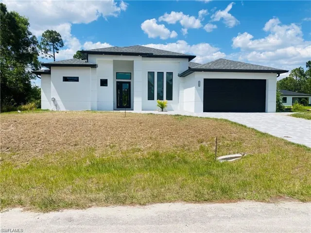 Prairie-style house featuring an attached garage, stucco siding, decorative driveway, and a front yard
