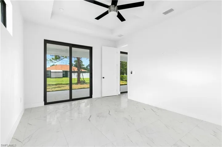 Empty room with marble look tile flooring, healthy amount of natural light, and a ceiling fan