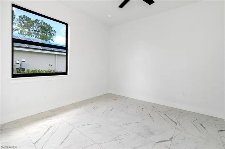 Unfurnished room featuring marble look tile flooring and ceiling fan