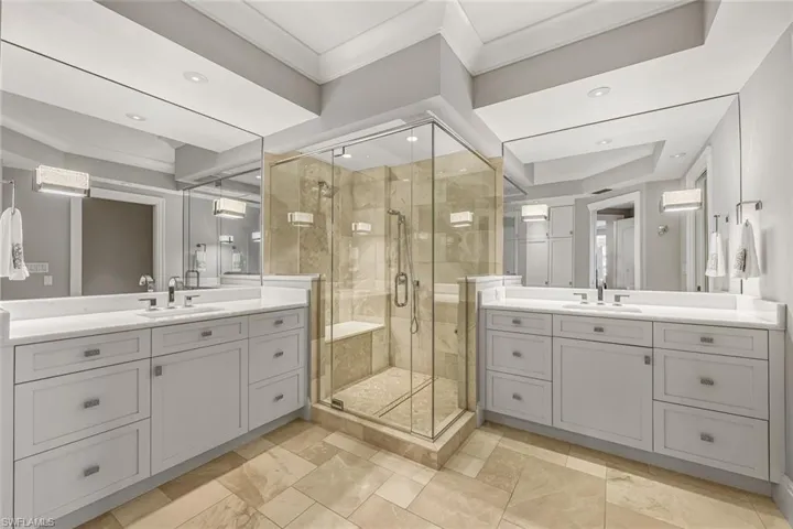 The primary bathroom offers dual vanities, a spacious walk-in shower, and abundant custom lighting.