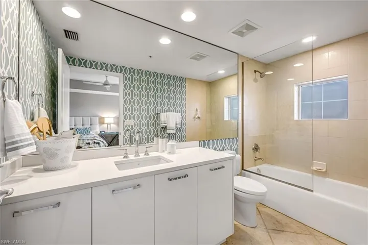 En-suite guest bathroom with custom wallpaper and glass shower enclosure.