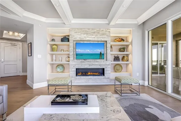 The entertainment wall features a gas fireplace, built in shelving and custom lighting.