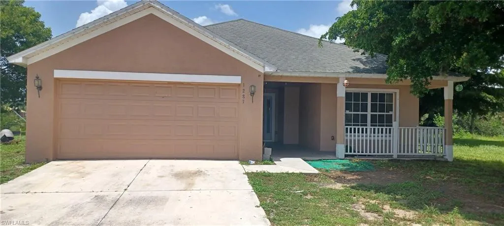 Single story home with roof with shingles, a porch, a garage, stucco siding, and concrete driveway