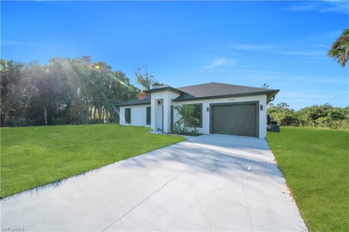 Contemporary ranch-style home featuring a dark shingle roof, white exterior, and a dark garage door