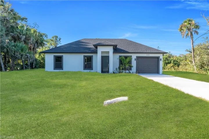 Modern stucco exterior with a dark shingle roof, attached garage, and a concrete driveway