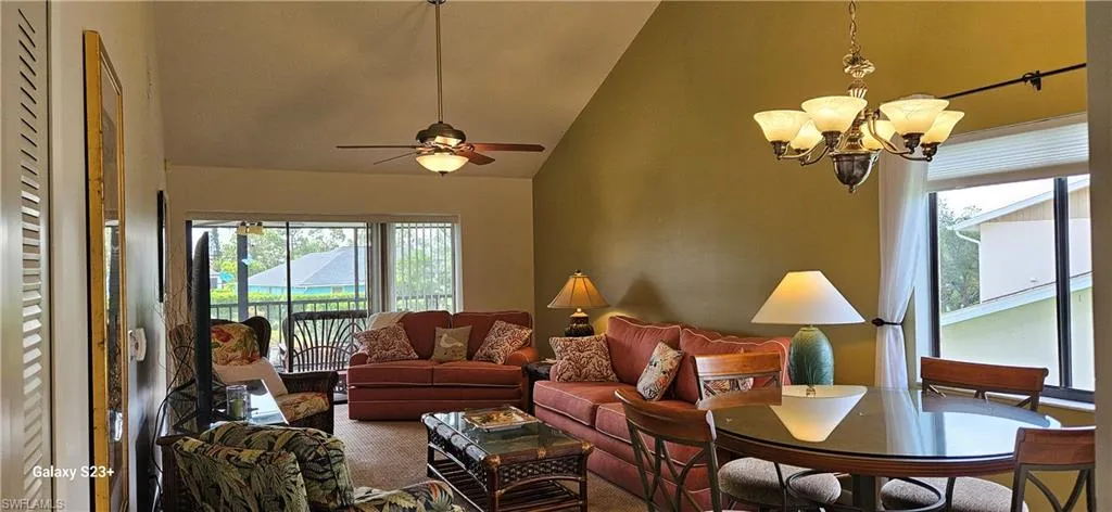 Living area featuring a chandelier, carpet floors, a ceiling fan, and high vaulted ceiling