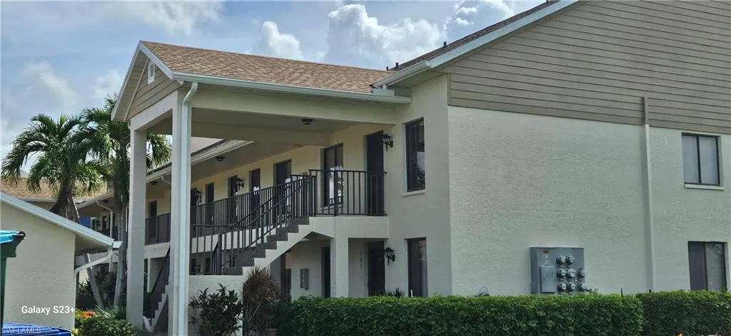 View of home's exterior featuring stucco siding, stairway, and roof with shingles