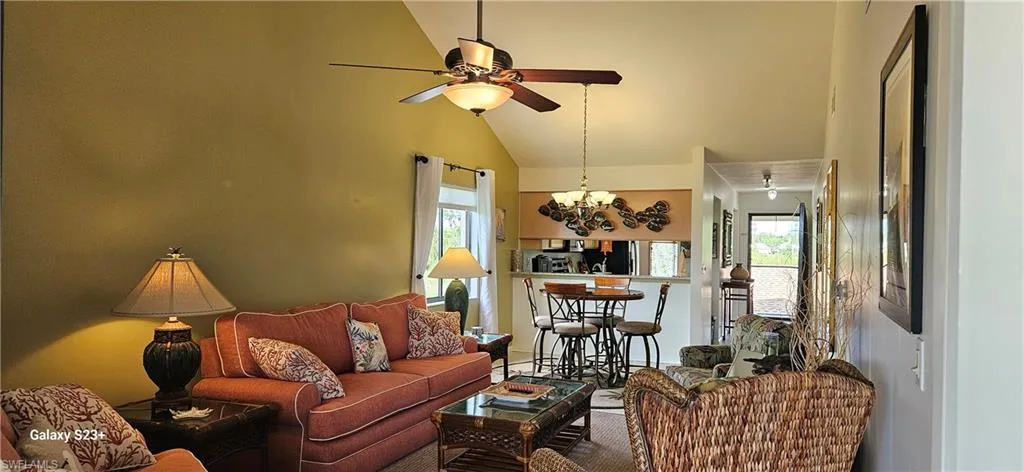 Living room with plenty of natural light, ceiling fan, a chandelier, and high vaulted ceiling