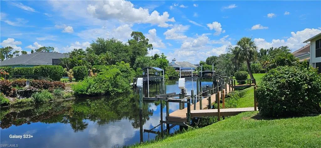 Dock with boat lift, a water view, and a lawn