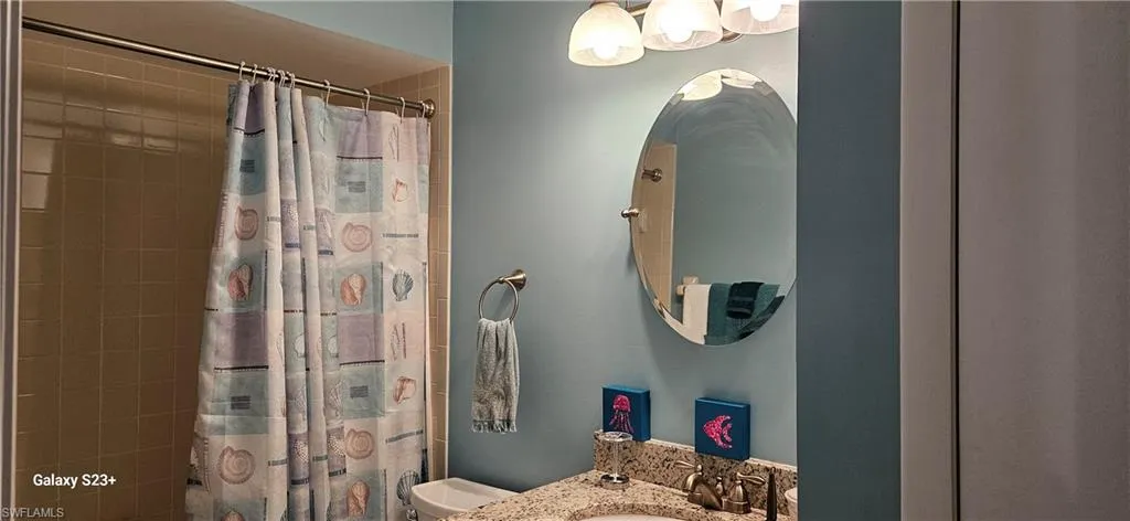 Bathroom featuring a shower with shower curtain and vanity