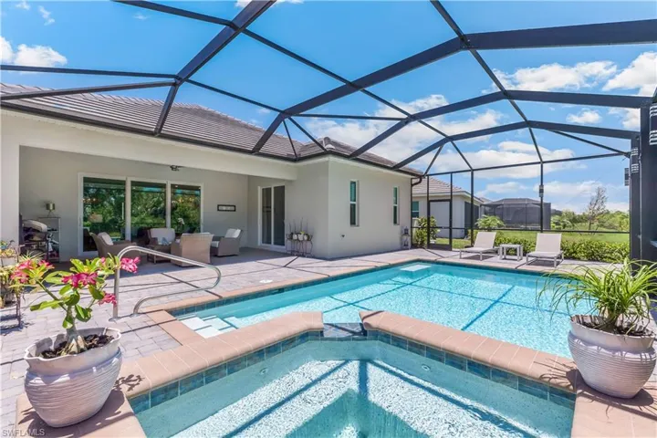 View of swimming pool featuring a patio, glass enclosure, and an in ground hot tub