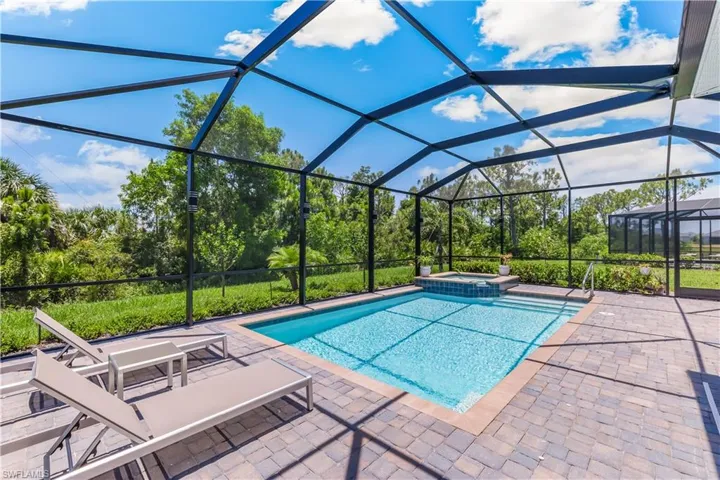 View of pool featuring a patio, glass enclosure, and an in ground hot tub