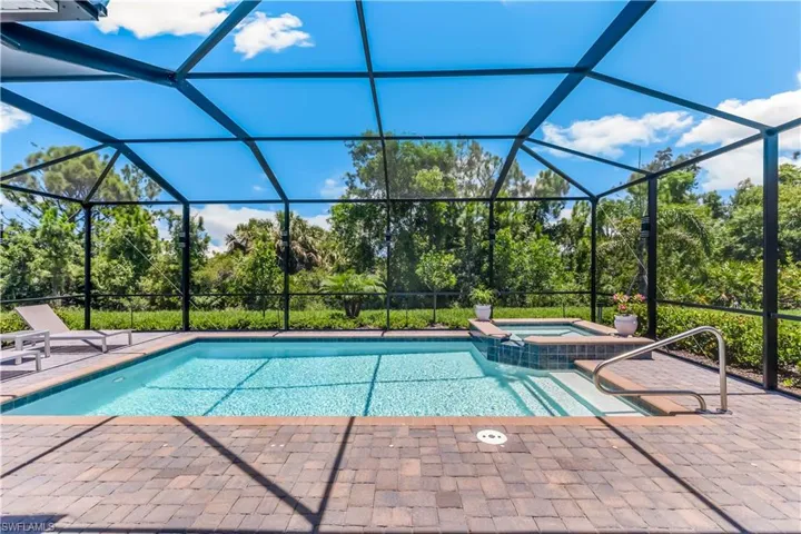 View of swimming pool featuring an in ground hot tub, a patio, and a lanai