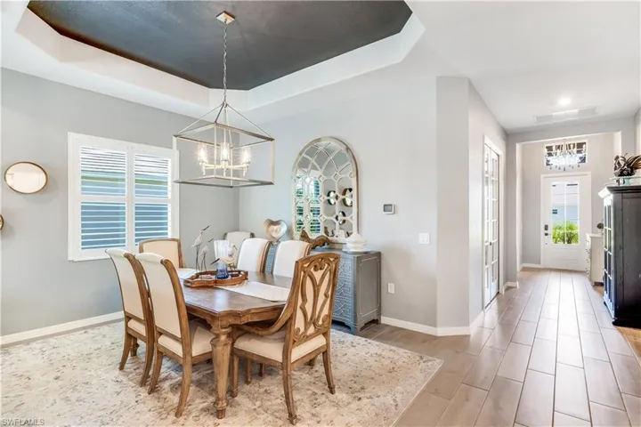 Dining room with a raised ceiling, a healthy amount of sunlight, and an inviting chandelier