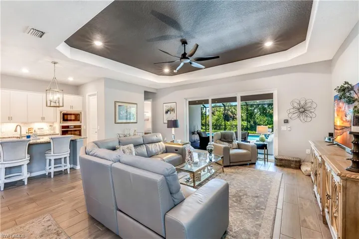 Living room featuring a tray ceiling, a textured ceiling, ceiling fan, and light hardwood / wood-style flooring