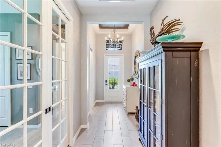 Doorway with tile floors, a raised ceiling, french doors, and a chandelier