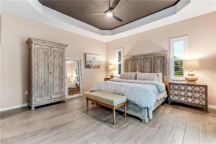 Bedroom featuring wood-type flooring, ceiling fan, and a raised ceiling