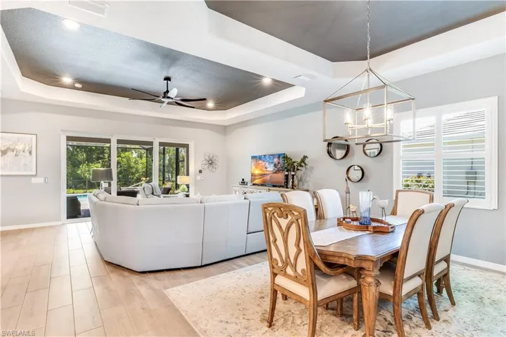 Dining room featuring a tray ceiling, ceiling fan with notable chandelier, and light hardwood / wood-style flooring