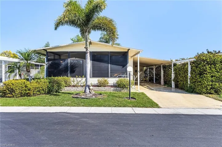 View of front of property featuring an attached carport, concrete driveway, and a sunroom