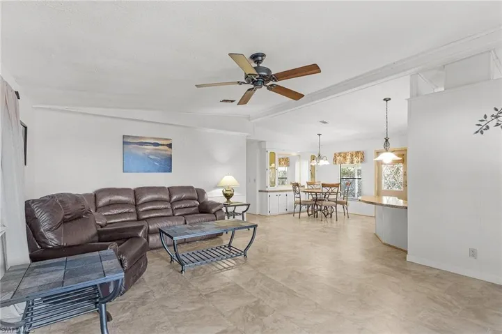 Living room featuring visible vents, vaulted ceiling with beams, and a ceiling fan