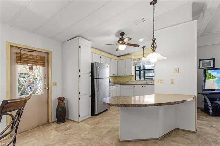 Kitchen with a ceiling fan, visible vents, freestanding refrigerator, hanging light fixtures, and dishwasher
