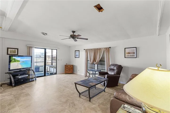 Living area featuring visible vents, baseboards, lofted ceiling with beams, and ceiling fan