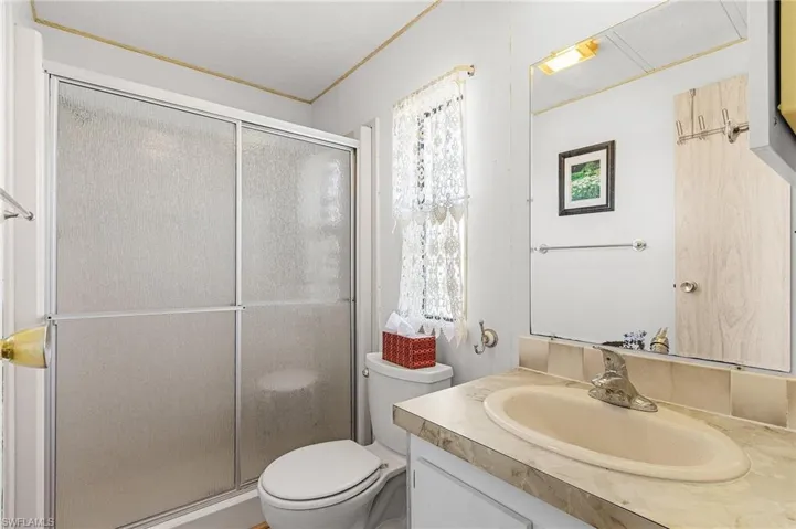 Bathroom featuring a shower stall, toilet, and vanity