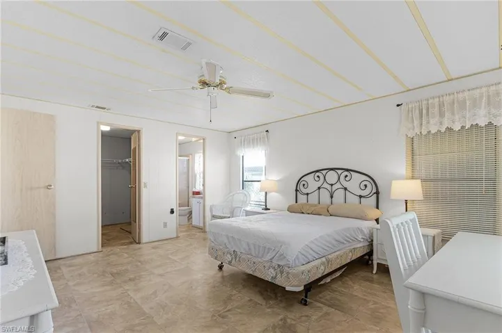 Bedroom with a walk in closet, a ceiling fan, visible vents, and a closet