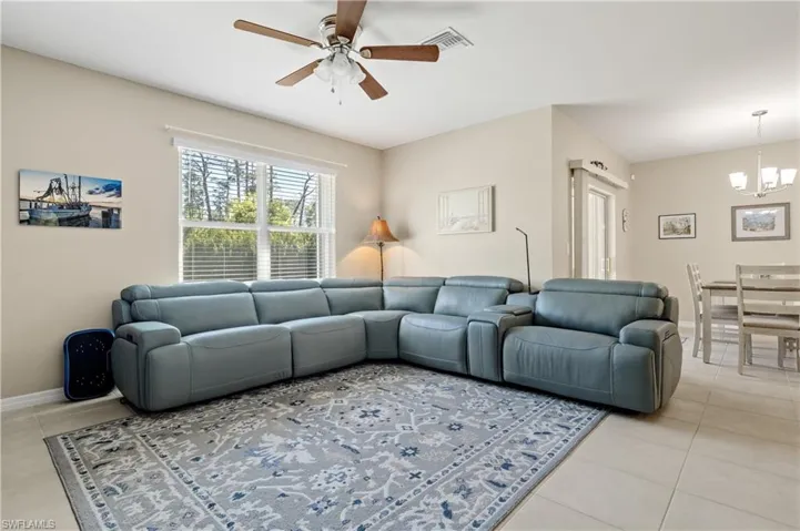 Living room featuring light tile patterned floors, ceiling fan, and hanging lights