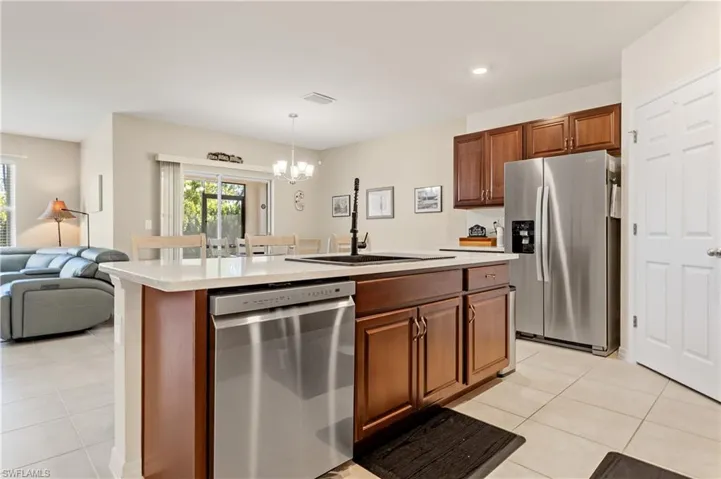 Kitchen with stainless steel appliances, open floor plan, a chandelier, light tile patterned floors, and an island with sink