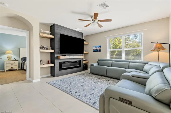 Living area with a ceiling fan and light tile patterned flooring