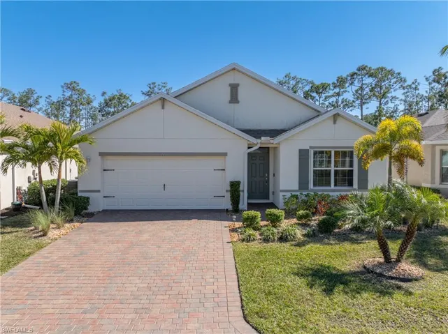 Ranch-style house with stucco siding, a front yard, decorative driveway, and an attached garage